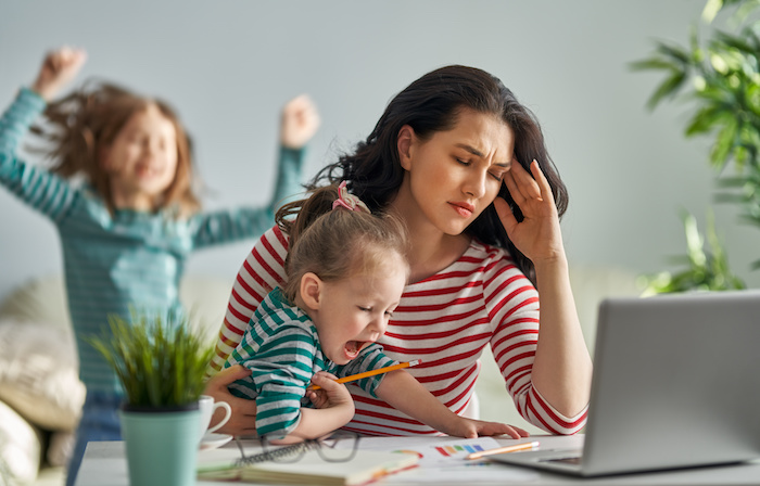 woman working on a laptop at home with children yelling