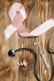Pink Ribbon womens breast cancer awareness with stethoscope on pink wood table with ribbon symbol.