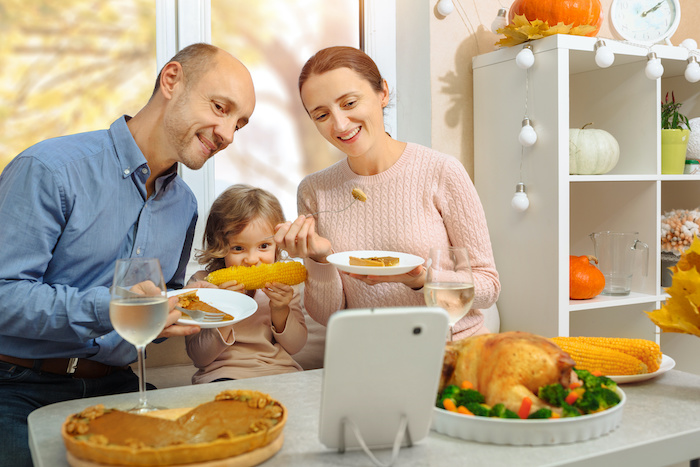 A happy family have a thanksgiving dinner and sends a video greeting to their parents .