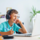 cheerful boy with headphones uses laptop for online school