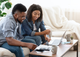 Smiling Black Couple Discussing Finances At Home
