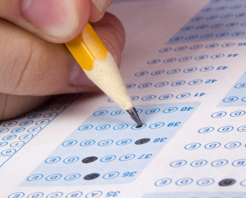 a student uses a pencil to fill in bubbles on a standardized test