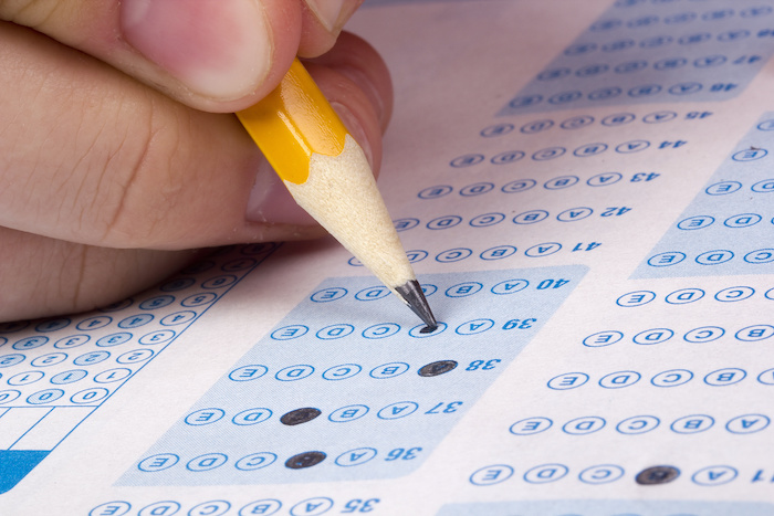 a student uses a pencil to fill in bubbles on a standardized test