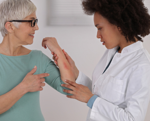 An image of a female African American doctor checking a rash on a female Caucasian. Skin Health