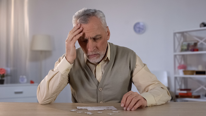 Older man trying to combine puzzle, having memory problems, cognitive impairment