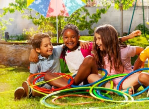 Three kids enjoy a summer day with hula hoops. The FEEA is here to assist you in choosing a summer camp they'll love.