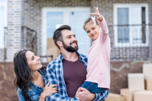 A family celebrates moving in to their new home holding up a set of keys.