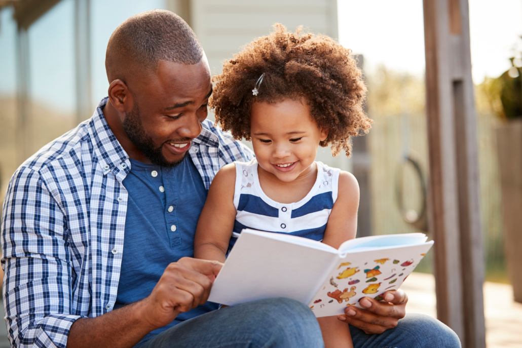 As part of Read Across America Day, a young black father and daughter read a book outside