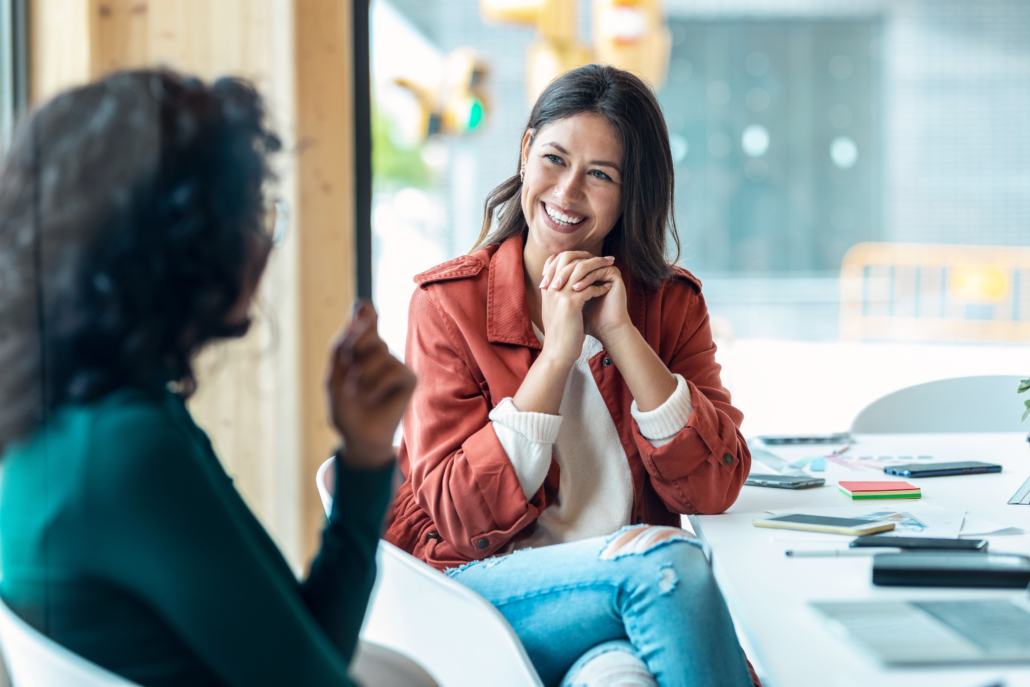 Two women talk in the office. Mentors can be an incredible source for guidance as you explore avenues for federal career growth.