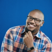 Alex Tremble smiles for the camera in front of a blue background