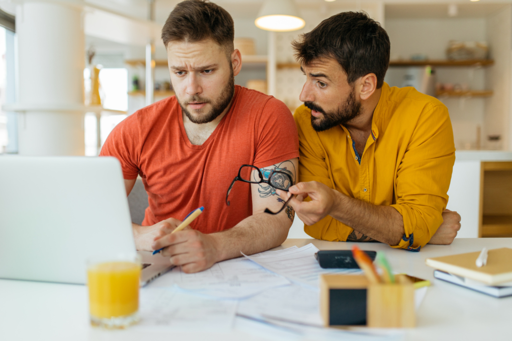 Two men working on their finances on a computer together. Keeping track of your spending is a critical point towards financial wellness for federal employees. 