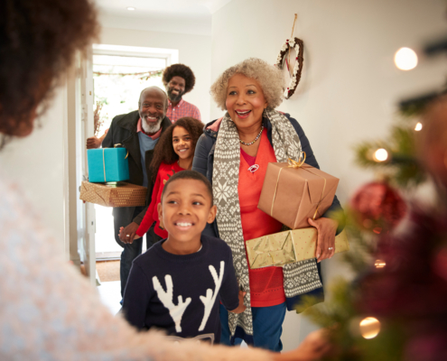 A family walks in the front door during the holiday season bearing gifts. Holiday budgeting tips with effective holiday financial planning can help keep your spending in line this season.
