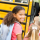 A little girl smiles for the camera as she boards a school bus for back-to-school and beginning of the school year.