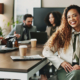 A woman smiles as coworkers collaborate in the background of a conference room. Strong teams and culture, clear expectations, and a healthy work life balance can lead to reduced workplace stress and workplace anxiety for federal employees.