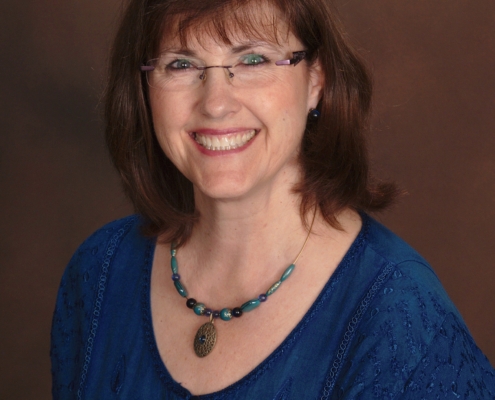 Kelly Reyes, a smiling white woman with brown hair and blue eyes